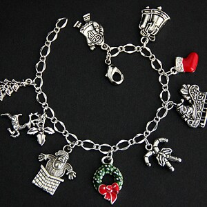 May include: A silver charm bracelet with Christmas-themed charms, including a Santa Claus, a reindeer, a Christmas tree, a stocking, a candy cane, a wreath, and a bell.