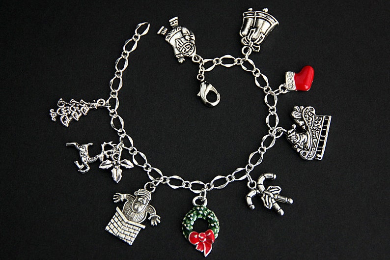 May include: A silver charm bracelet with Christmas-themed charms, including a Santa Claus, a reindeer, a Christmas tree, a stocking, a candy cane, a wreath, and a bell.