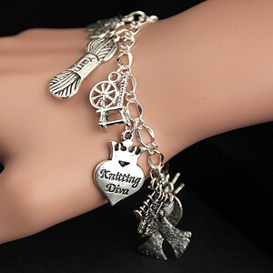May include: Silver charm bracelet with multiple charms, including a yarn ball, a spinning wheel, a heart with the text "Knitting Diva", and a pair of angel wings.