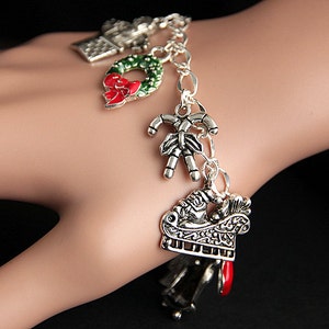 May include: Silver charm bracelet with Christmas themed charms, including a wreath, candy cane, and a sleigh.