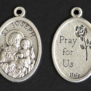 Peut inclure: Pendentif ovale en argent avec une repr&eacute;sentation de Saint Joseph tenant l'enfant J&eacute;sus d'un c&ocirc;t&eacute; et les mots "Priez pour nous" et une rose de l'autre. Le pendentif est fabriqu&eacute; en Italie.