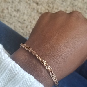 woman wearing a small, thin rose gold plated Singapore double chain bracelet, a curb chain that twists on itself.