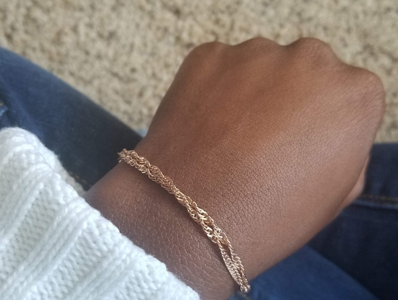 woman wearing a small, thin rose gold plated Singapore double chain bracelet, a curb chain that twists on itself.