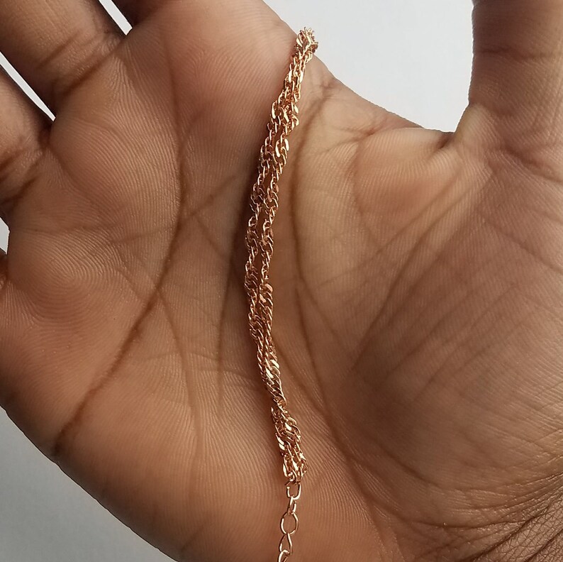 double Singapore chain bracelet, a curb chain that twists on itself, in a woman's hand.