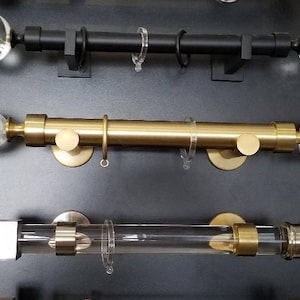 May include: Three different curtain rods with decorative finials. The top rod is black with clear glass finials. The middle rod is gold with clear glass finials. The bottom rod is gold with a clear glass tube and gold finials.