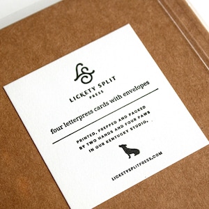 May include: A white card with black text and a small black dog silhouette. The text reads "& LICKETY SPLIT PRESS four letterpress cards with envelopes PRINTED, PREPPED AND PACKED BY TWO HANDS AND FOUR PAWS IN OUR KENTUCKY STUDIO, LICKETYSPLITPRESS.COM"