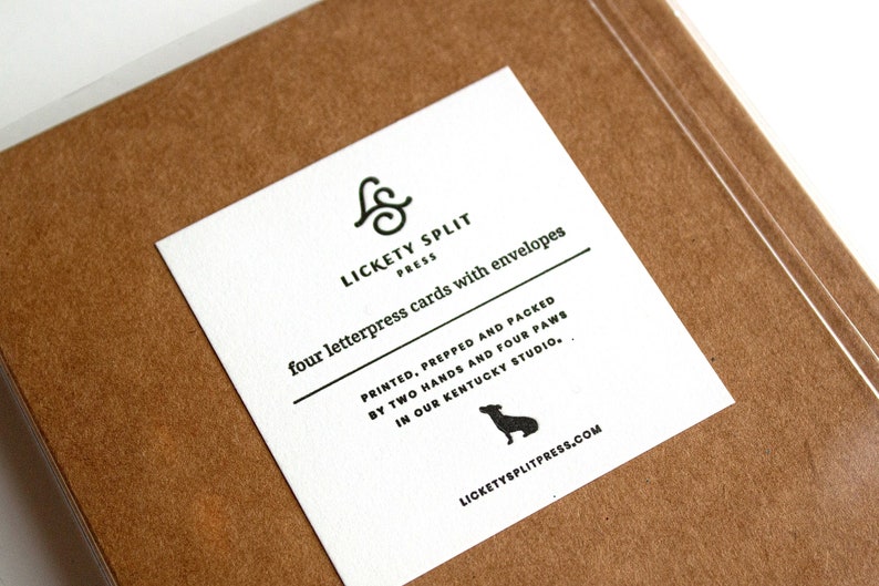 May include: A white card with black text and a small black dog silhouette. The text reads "& LICKETY SPLIT PRESS four letterpress cards with envelopes PRINTED, PREPPED AND PACKED BY TWO HANDS AND FOUR PAWS IN OUR KENTUCKY STUDIO, LICKETYSPLITPRESS.COM"