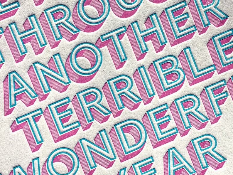 May include: Close-up of a pink and blue graphic design with the text "Through another terrible wonderful year".