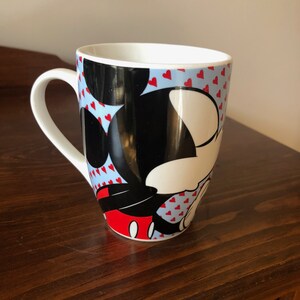 Pu&ograve; includere: Tazza in ceramica bianca con sfondo blu e cuori rossi. Topolino &egrave; raffigurato sulla tazza in nero, bianco e rosso.