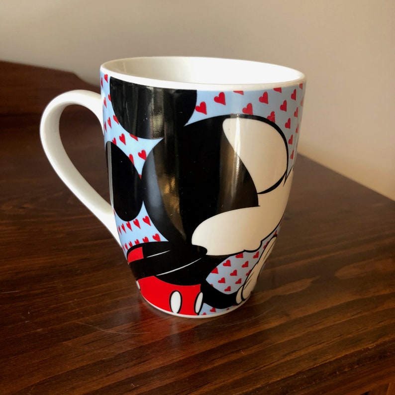 Pu&ograve; includere: Tazza in ceramica bianca con sfondo blu e cuori rossi. Topolino &egrave; raffigurato sulla tazza in nero, bianco e rosso.