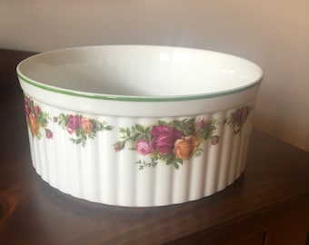 May include: White ceramic serving dish with a green rim and vertical ribbed sides. The dish is decorated with a floral pattern of pink, red, and yellow roses. A decorative piece for the kitchen.