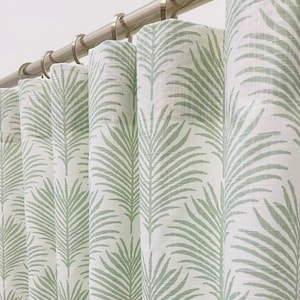 May include: White and light green palm leaf patterned curtains hanging from a silver rod with rings. The curtains are made of a textured fabric and are partially closed, showing the repeating leaf design.