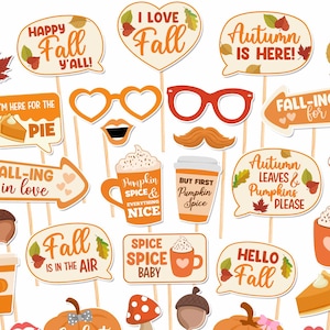 May include: A collection of autumn-themed photo booth props on sticks, featuring orange and brown pumpkins, mushrooms, acorns, leaves, glasses, lips, mustaches, and speech bubbles with text like Happy Fall Y'all, Autumn is Here, and Pumpkin Spice.
