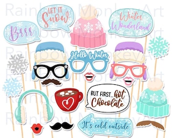 May include: A collection of winter-themed photo booth props on sticks, including speech bubbles with text like Let It Snow, Winter Wonderland, Hello Winter, But First Hot Chocolate, and It's Cold Outside, plus hats, glasses, mustaches, and snowflakes.