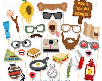 May include: A collection of camping-themed photo booth props on sticks, including a beehive, bear ears, sunglasses, a sign reading DON'T FEED THE BEARS, a flashlight, s'mores, a camera, a compass, a lantern, binoculars, and a pocket knife.