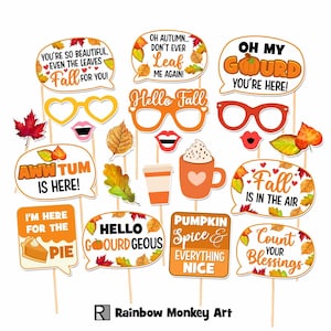 May include: A collection of autumn-themed photo booth props on sticks, including speech bubbles with text like 'Oh My Gourd', 'Hello Fall', and 'Fall Is In The Air', alongside cutouts of glasses, lips, leaves, a coffee cup, and a slice of pumpkin pie.