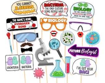 May include: A collection of science-themed photo booth props on sticks, including speech bubbles with puns, a microscope, safety goggles, a petri dish, a test tube, a beaker, a magnifying glass, a bow tie, a mustache, and lips on a white background.