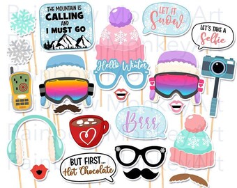 May include: A collection of winter-themed photo booth props on sticks, including signs with text like The Mountain Is Calling, Let It Snow, Let's Take A Selfie, Hello Winter, Brrr, and But First Hot Chocolate, alongside hats, goggles, glasses, and cocoa.