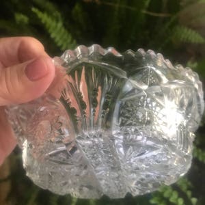 Puede incluir: Un cuenco de vidrio transparente con un borde festoneado y un intrincado dise&ntilde;o de vidrio cortado. El cuenco est&aacute; hecho de cristal y tiene un aspecto vintage.