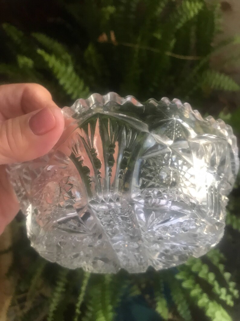 Puede incluir: Un cuenco de vidrio transparente con un borde festoneado y un intrincado dise&ntilde;o de vidrio cortado. El cuenco est&aacute; hecho de cristal y tiene un aspecto vintage.