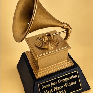 Può includere: Un trofeo color oro a forma di tromba di grammofono montato su una base quadrata. La targa nera sul davanti presenta il testo dorato: Texas Jazz Competition First Place Winner 2024. L'intera struttura ha una finitura metallica.