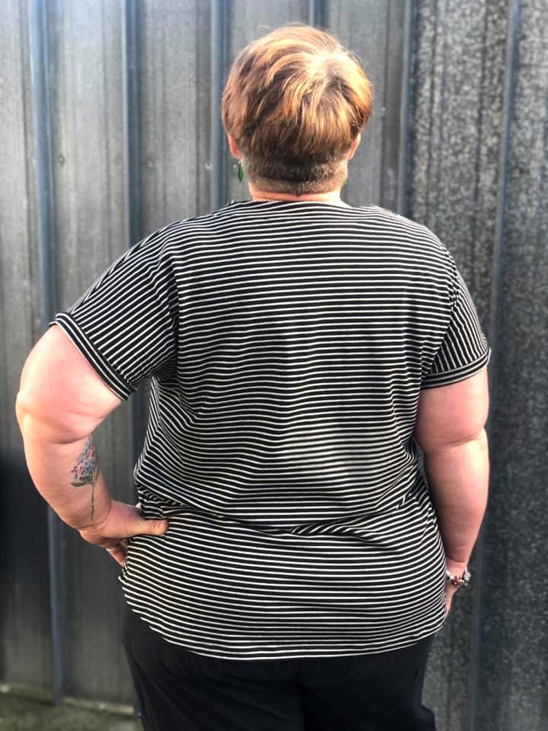 May include: A black and white striped shirt with short sleeves. The shirt is loose fitting and has a relaxed fit.