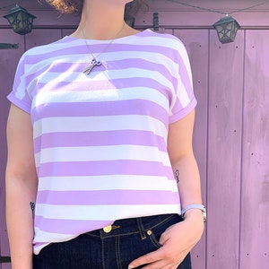以下が含まれることがあります： 紫と白のストライプのTシャツに、金色のチェーンネックレスとハサミのペンダントがついたもの