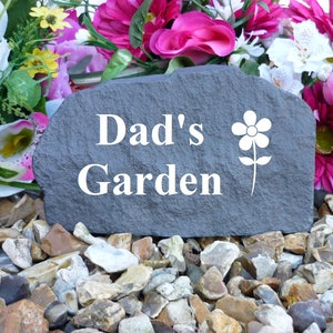 May include: A gray stone garden marker with the text "Dad's Garden" and a white flower design.