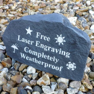 May include: A black slate rock with white text that reads "Free Laser Engraving Completely Weatherproof". The text is surrounded by symbols including a star, sun, snowflake, and umbrella.