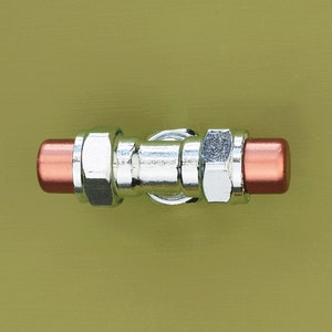 Puede incluir: Una válvula de fontanería cromada con tapas de cobre en los extremos. La válvula está montada en una pared verde.