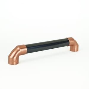 May include: Black and copper industrial style cabinet pull. The pull is made of a black metal pipe with copper end caps.