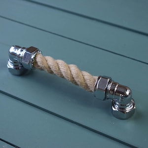 Puede incluir: Un tirador de armario de cuerda cromado con un centro de cuerda natural. El tirador tiene forma de ángulo de 90 grados.