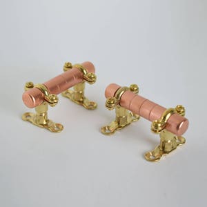 Pode incluir: Duas puxadores de gaveta de cobre e latão com um design steampunk. Os puxadores são feitos de tubo de cobre e acessórios de latão.