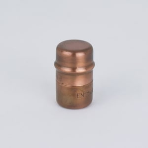 Pode incluir: Uma conexão de tubo de metal de cor cobre com o texto "EN1254" gravado no lado.