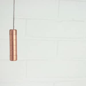 Puede incluir: Una cadena de tracción de color cobre para una lámpara cuelga de un techo blanco.