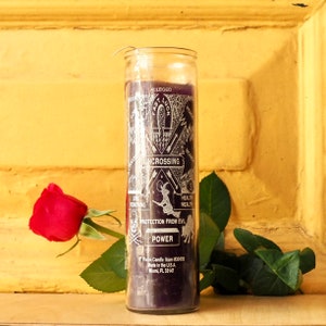 Könnte beinhalten: Eine violette Kerze mit weißem Text und Symbolen, darunter "Alleged Fast Luck", "Uncrossing", "Health Wealth", "Protection From Evil" und "Power". Die Kerze befindet sich in einem Glasgefäß und hat einen weißen Docht.