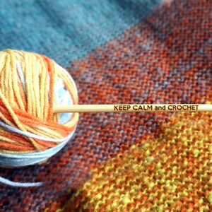 May include: A ball of yellow, orange, and white yarn with a wooden knitting needle that says "KEEP CALM and CROCHET".