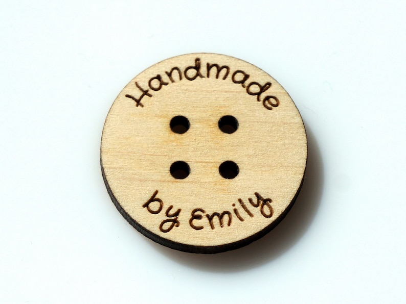 May include: A round wooden button with four holes and the text "Handmade by Emily" engraved on it.