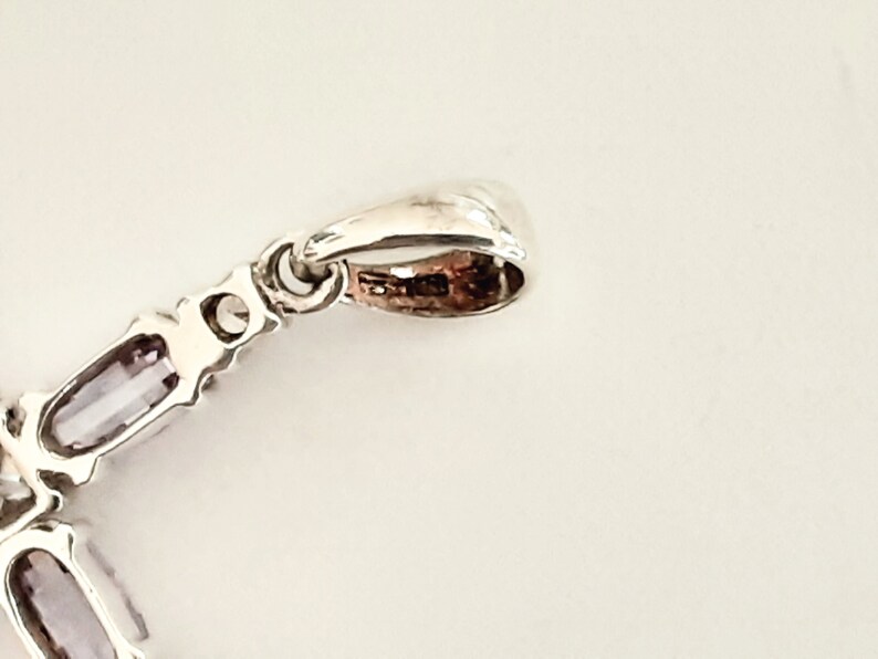 Pu&ograve; includere: Ciondolo in argento con una pietra preziosa viola e una baionetta in argento. La baionetta &egrave; un anello che serve per attaccare il ciondolo a una catena.