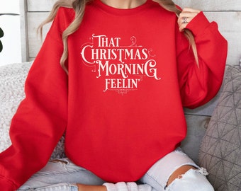 Pode incluir: Camisola vermelha com texto branco que diz "That Christmas Morning Feelin'".