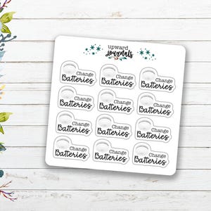 May include: A sheet of white stickers with the text "Change Batteries" in a handwritten font. The stickers have a small battery icon. The brand name "upward journals" is at the top of the sheet.