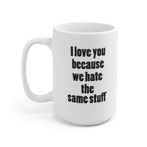 May include: White ceramic mug with a curved handle. The mug features the text "I love you because we hate the same stuff" in black, centered on the front. The mug is designed for hot beverages.