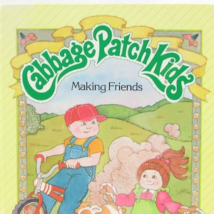 May include: A yellow book cover with the title "Cabbage Patch Kids Making Friends" in green and yellow lettering. The cover features an illustration of two Cabbage Patch Kids dolls, one riding a red bicycle and the other jumping rope.