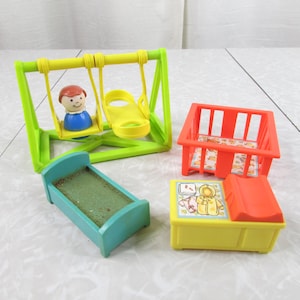 May include: A collection of vintage Fisher-Price Little People toys. Includes a green and yellow swing set with a figure, a teal bed, an orange crib, and a yellow changing table.