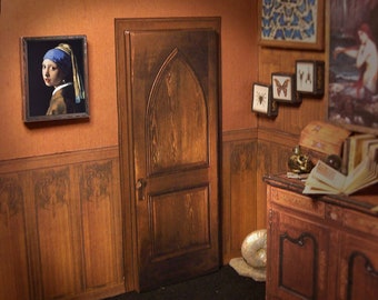 May include: A miniature dollhouse room featuring a wooden door, a wooden dresser, and a framed picture of a girl with a pearl earring. The walls are wood panelled with a floral pattern. There are several framed pictures of butterflies and a framed picture of a woman in a forest.