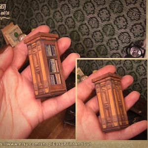 Op de afbeelding: Een miniatuur houten boekenkast met een gedetailleerd ontwerp, in een bruin en gouden kleurenschema. De boekenkast is gevuld met miniatuurboeken.
