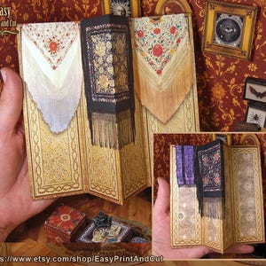 May include: A paper craft with a foldable design, showcasing floral and patterned details. It features a black shawl with gold floral patterns and fringe, and a white shawl with red floral accents. The text "Easy Print and Cut" is visible.