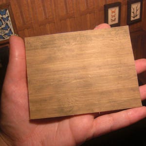 Pu&ograve; includere: Primo piano di un foglio di carta con texture effetto legno di colore marrone chiaro. La carta ha una superficie leggermente ruvida ed &egrave; tenuta in una mano.