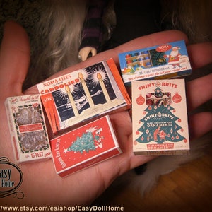 May include: A collection of vintage Christmas decorations in miniature boxes. The boxes are red, green, and white with images of Christmas lights, ornaments, and a Christmas tree. The text on the boxes reads "Noma Lites Candoler", "Shiny Brite", and "Shiny Brite Ornaments".