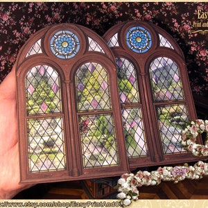 May include: A printable stained glass window design featuring a garden scene with a diamond pattern. The design is framed in a brown wooden frame with a decorative arch at the top. The text "Easy Print and Cut" is visible in the upper right corner.